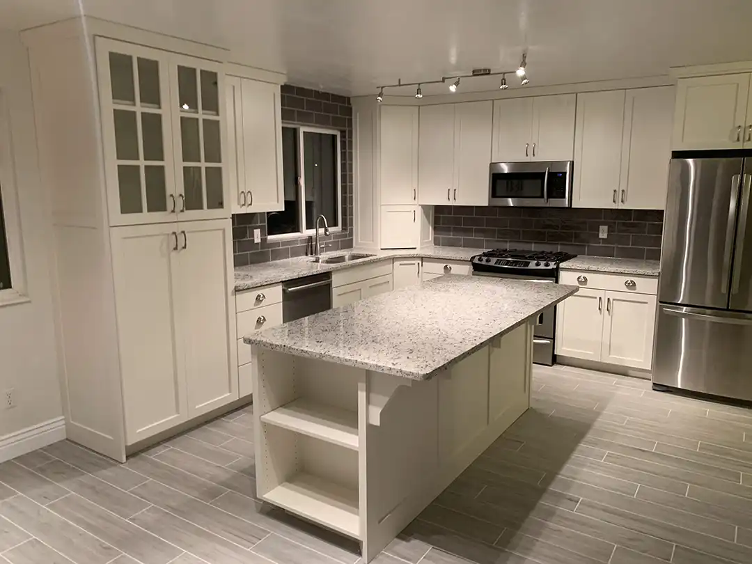 Photo of a small kitchen renovation with custom cabinets and an island with a countertop overhang.