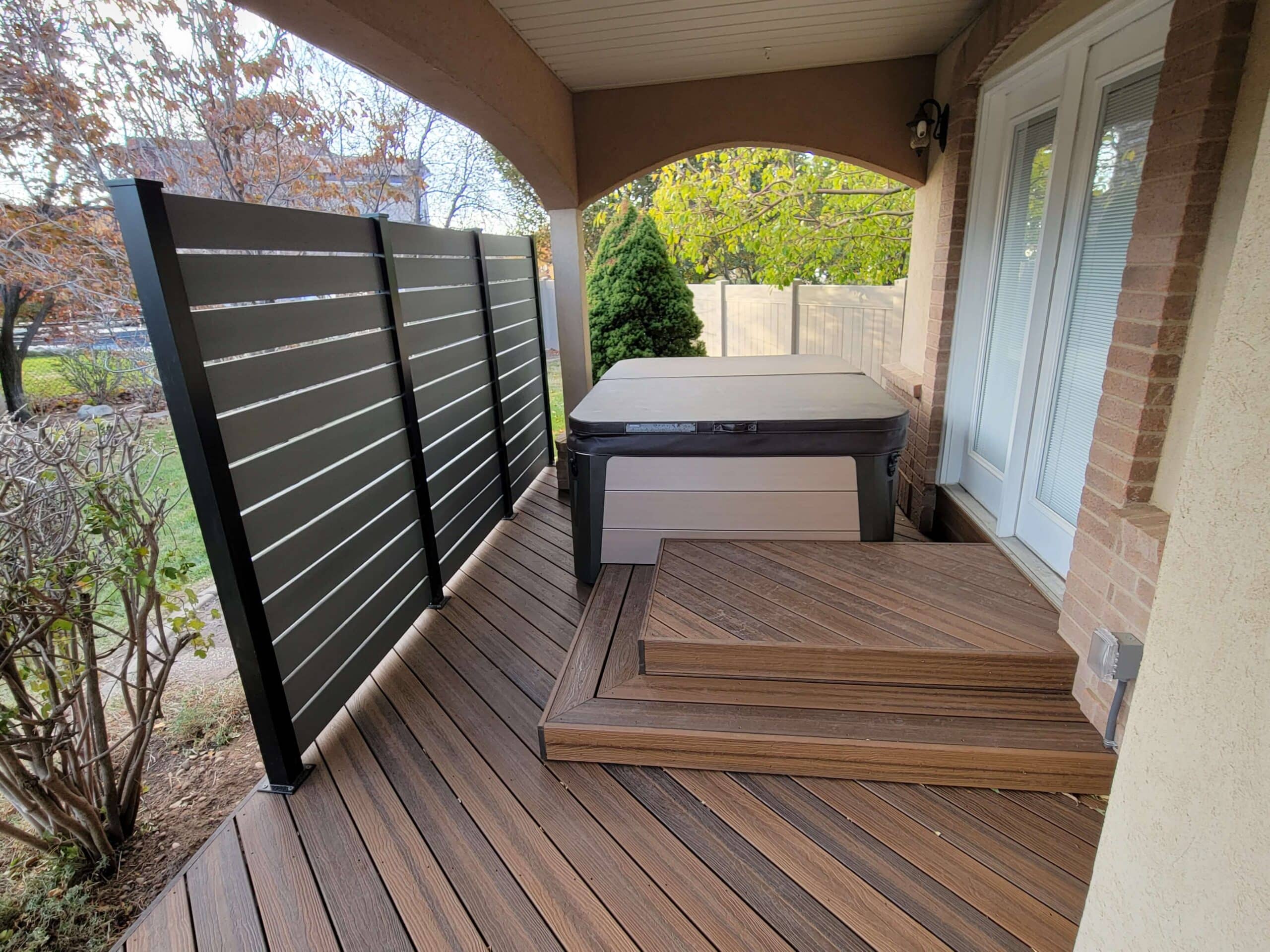 photo of a deck with privacy screen, hot tub, and step platform - Off-Season Deck Building