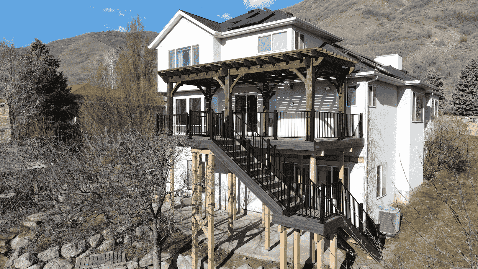 photo of an elevated deck built on a mountainside home with a traditional wooden pergola on the deck