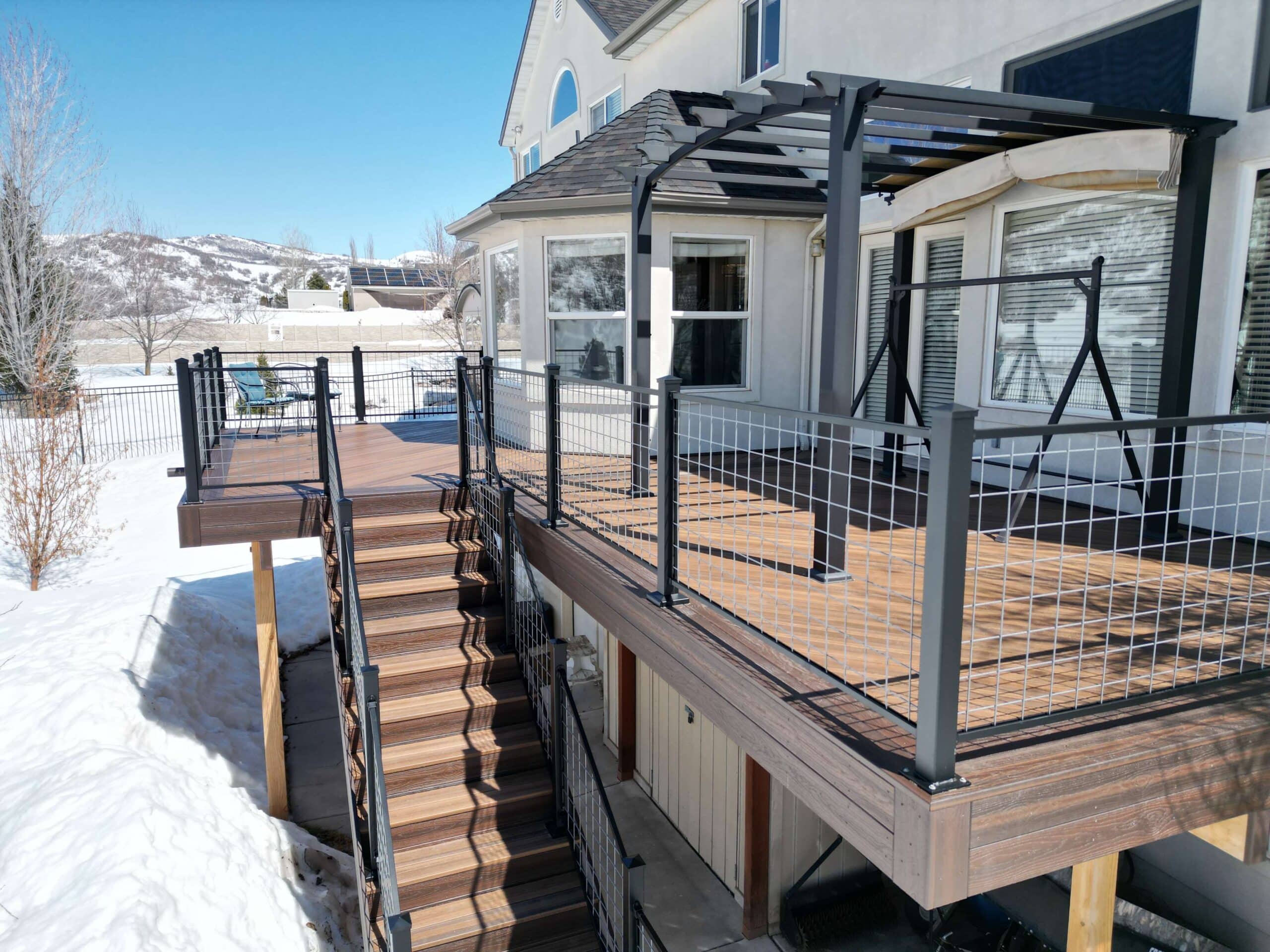 photo of elevated deck with cable railing and pergola surrounded by snow - Best Deck Builders for the Winter in Utah