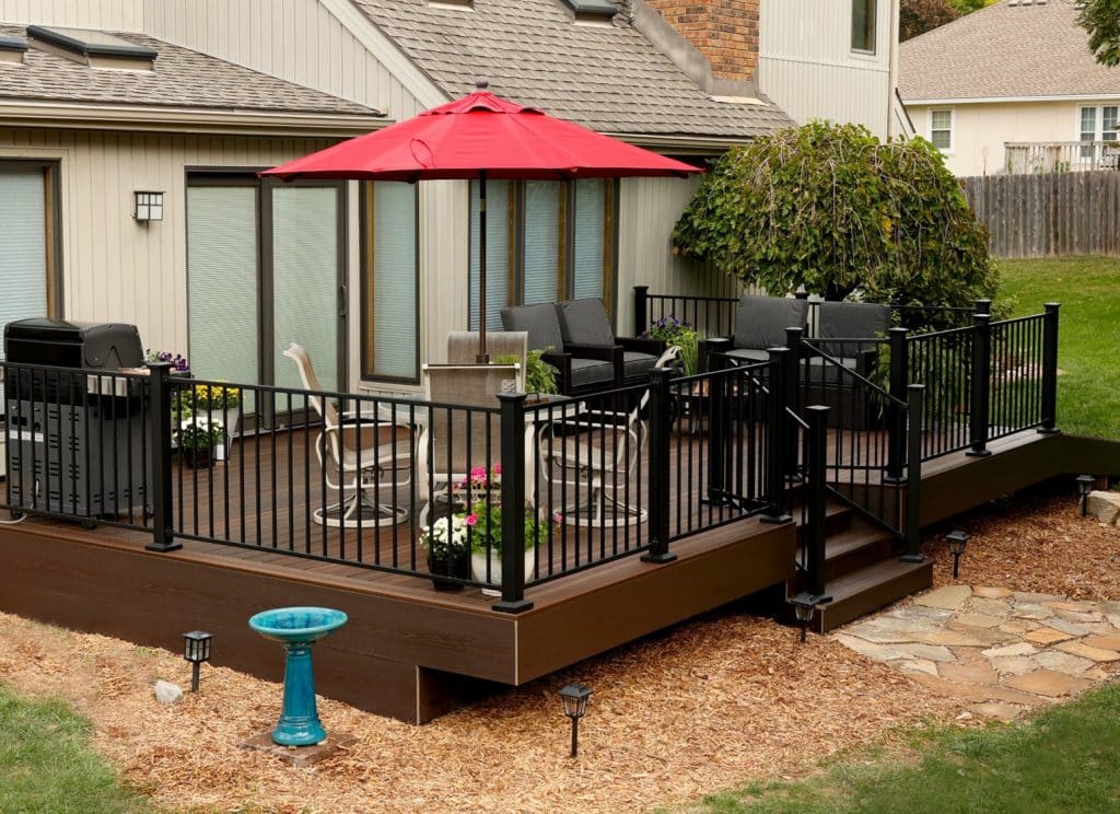 Black steel Fairway deck railing on a raised deck with outdoor furniture and umbrella